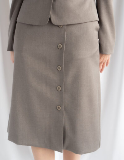 beżowa spódnica asymetryczna z guzikami i kieszeniami.